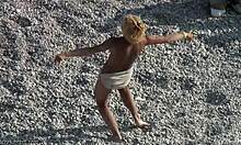 Zabavna blondinka pleše okoli v pesku